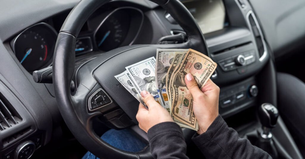 Person counting money on steering wheel in car