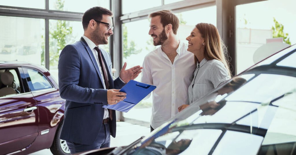 Used car salesman selling vehicle to couple