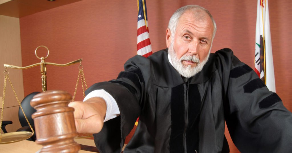 judge holding gavel next to scales of justice