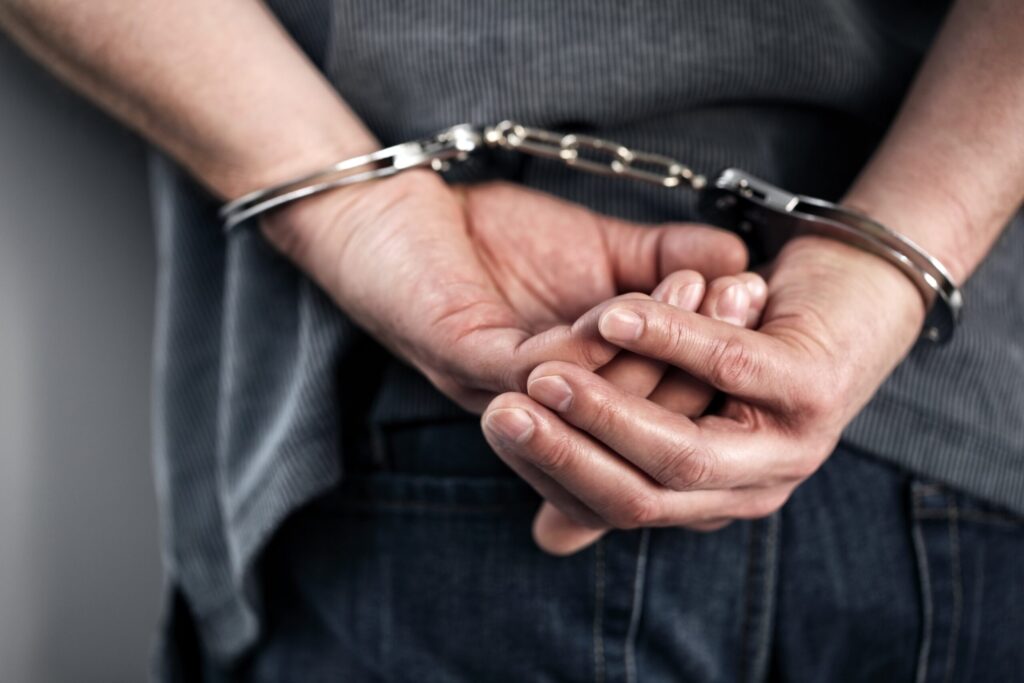 man with hands in handcuffs behind his back