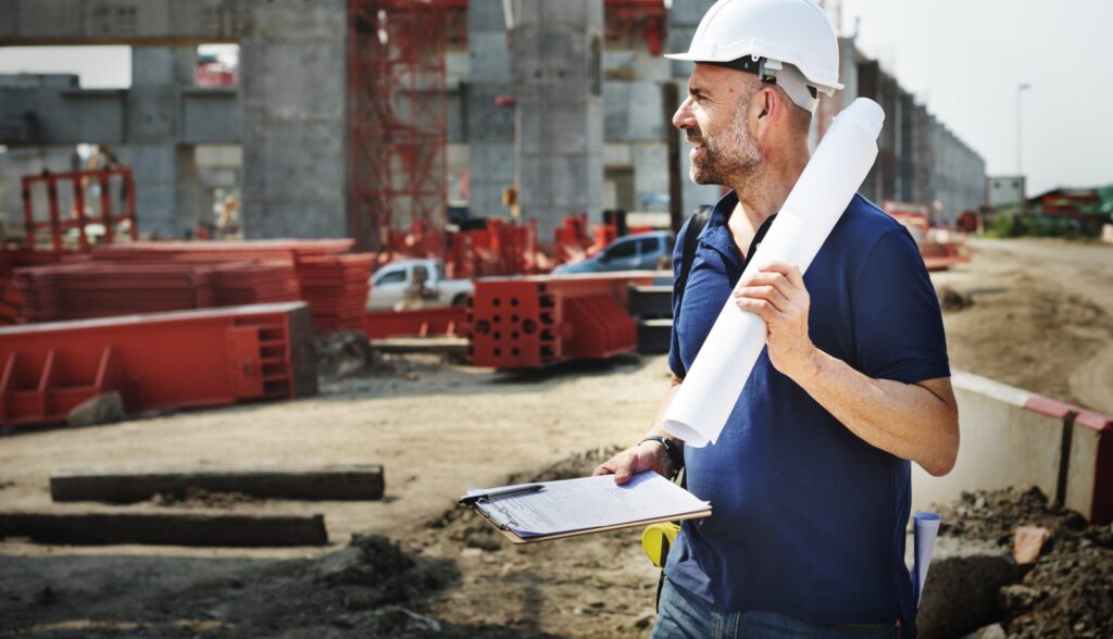 construction worker walking with clipboard and plans