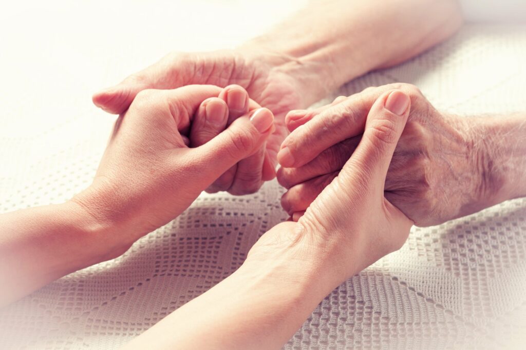 woman holding elderly mans hands