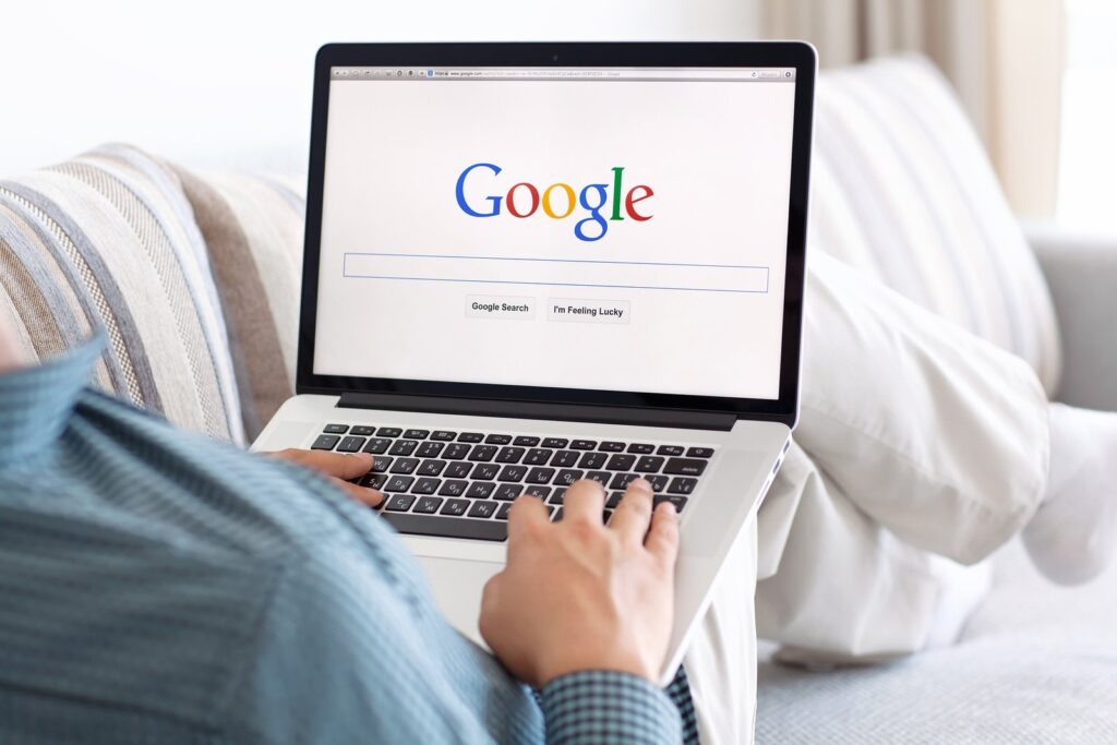 man using google on laptop while sitting on sofa