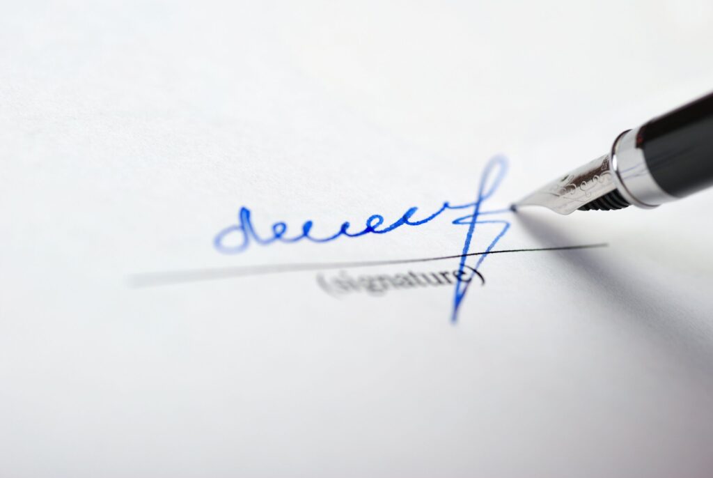 pen signing name on signature line