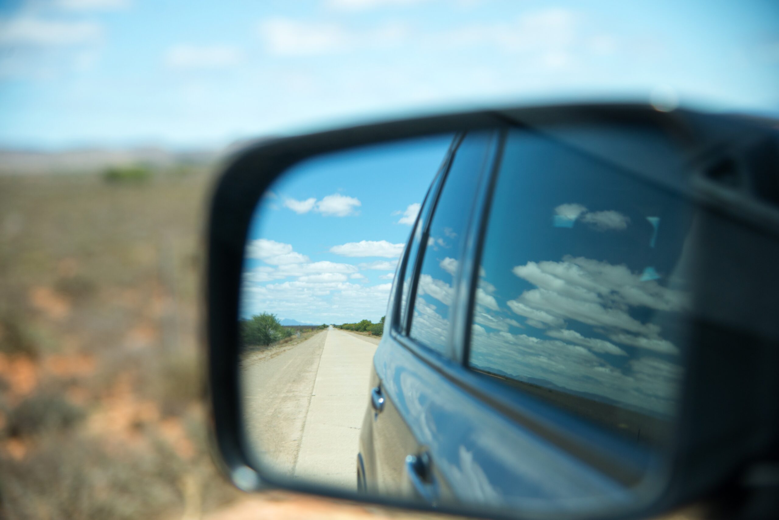 Side Mirror Of Vehicle Capturing The Background